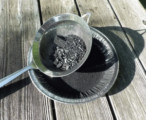 screening-the-charcoal-through-a-strainer